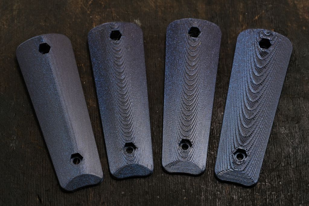 Fire rekkerthandtak i svart plast som er produserte med ulik grovleik. Handtaka med grovare struktur har fått ein struktur som minner om trevirke. Foto.