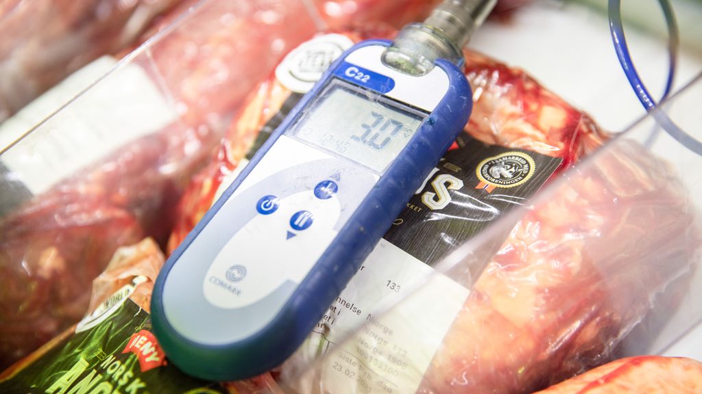 Termometer som viser tre grader, ligger på vakuumpakkede kjøttprodukter i en kjøledisk. Foto.
