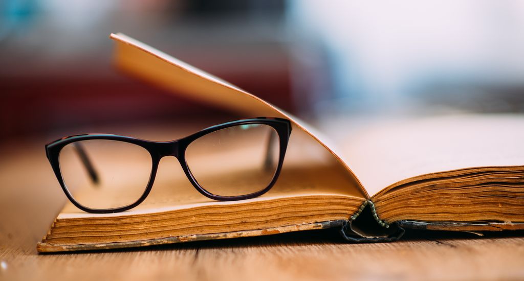 A pair of glasses lying on an old book. Photo.