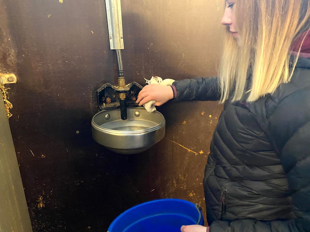 Kvinne tørker av en drikkeautomat. Foto.