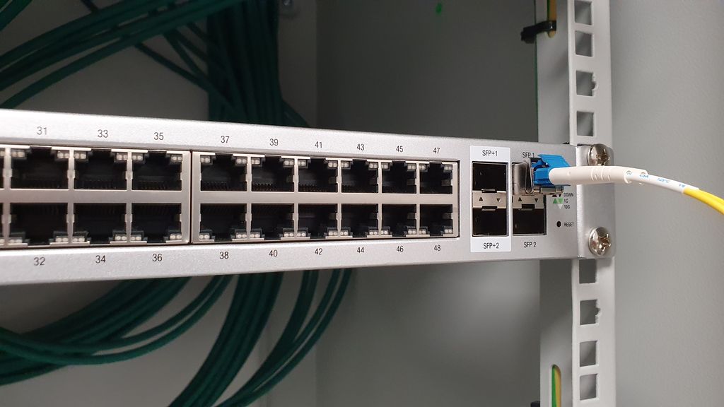 48-portersvitsj med SFP- og SFP+-porter helt til høyre. En av SFP-portene er fylt med en medieomformer for fiber. En fiberkabel er tilkoblet. Foto.
