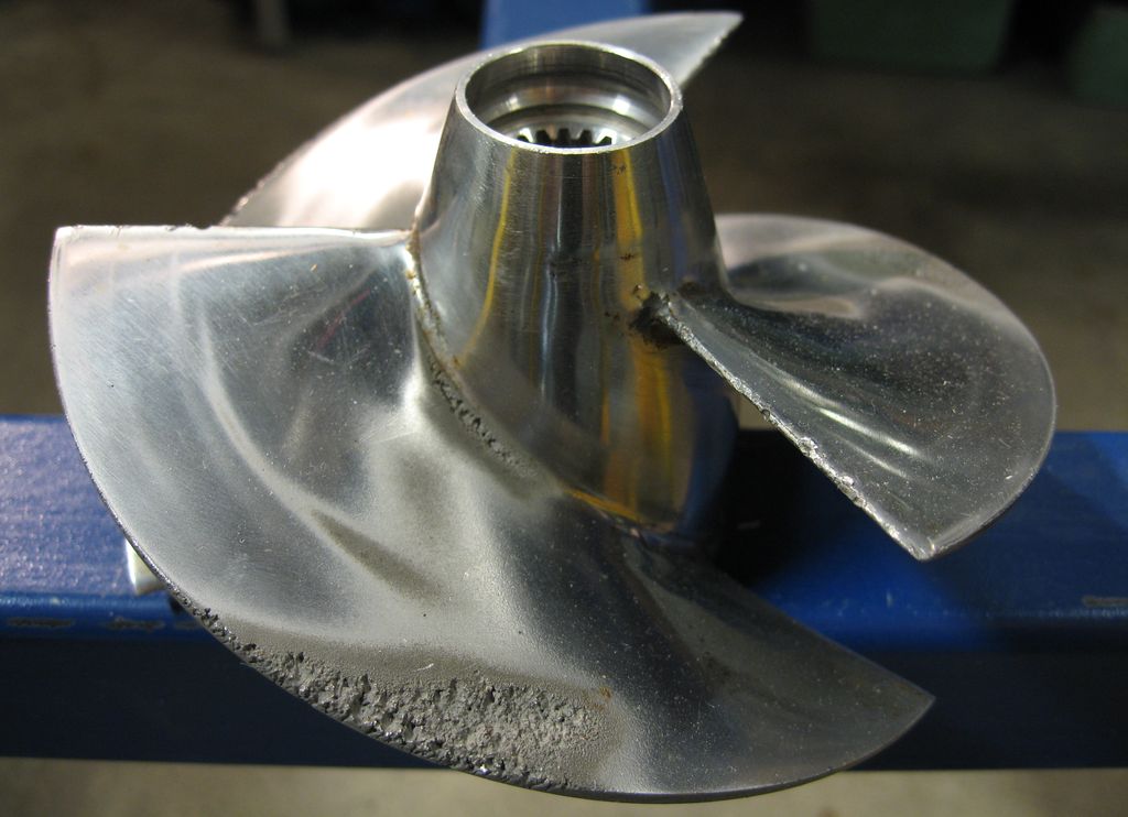 Båtpropell som ligger på et bord. Den har fått mindre tæringsskader ytterst på propellbladene. Foto.