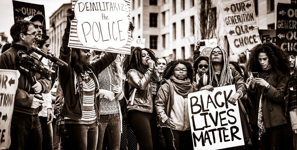 A group of people demonstrating, holding BlackLivesMatter signs. Black and white photo. 