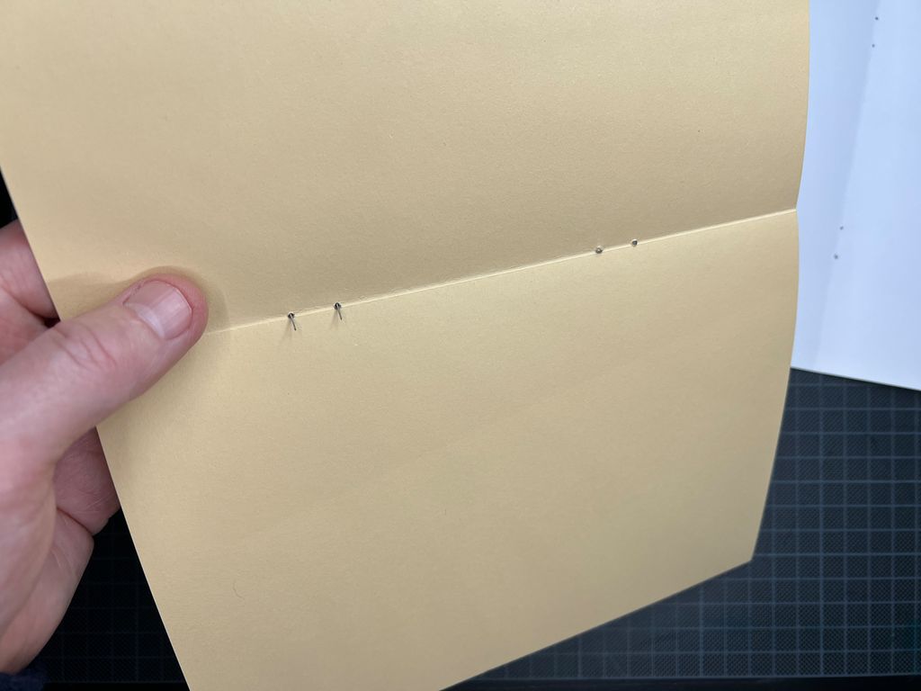 Et brettet ark med hull til stifter. Foto.