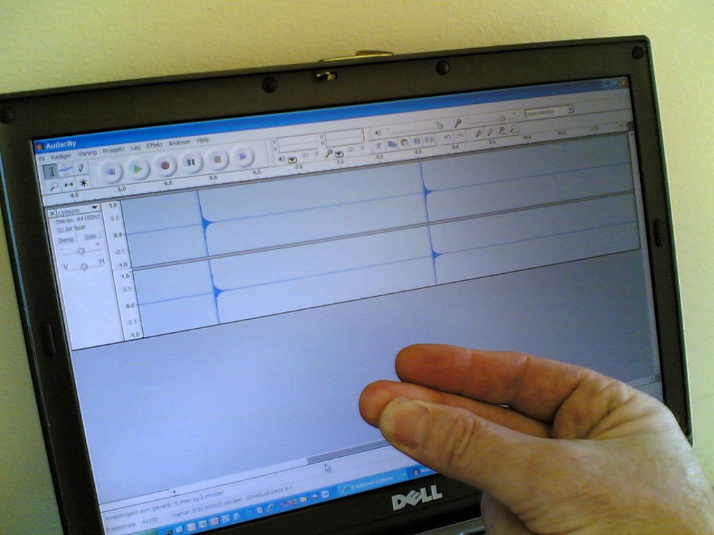 PC-skjerm og ei hand som knipser. Foto.