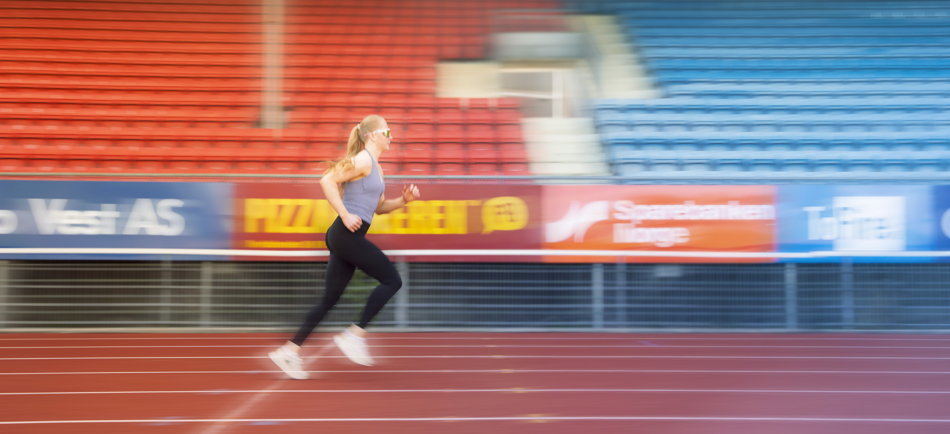 Jente jogger på et stadion. Foto.