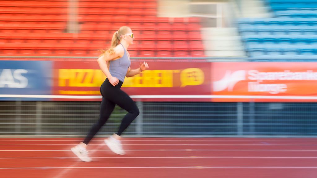Jente joggar på ein stadion. Foto.