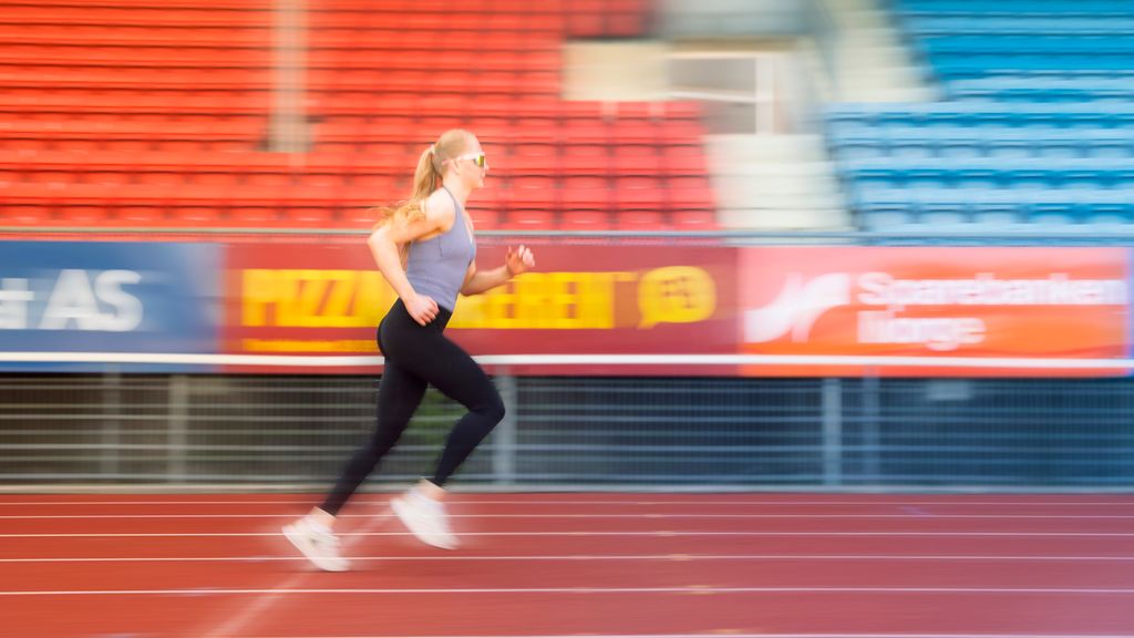 Jente jogger på et stadion. Foto.