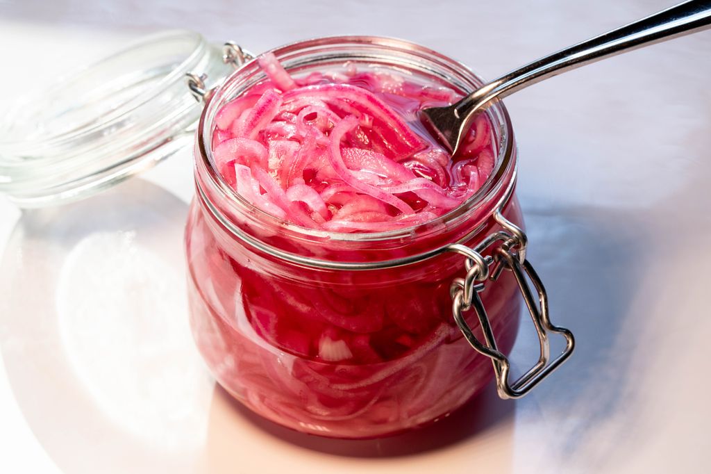 Et åpnet glass med syltet rødløk. Foto.