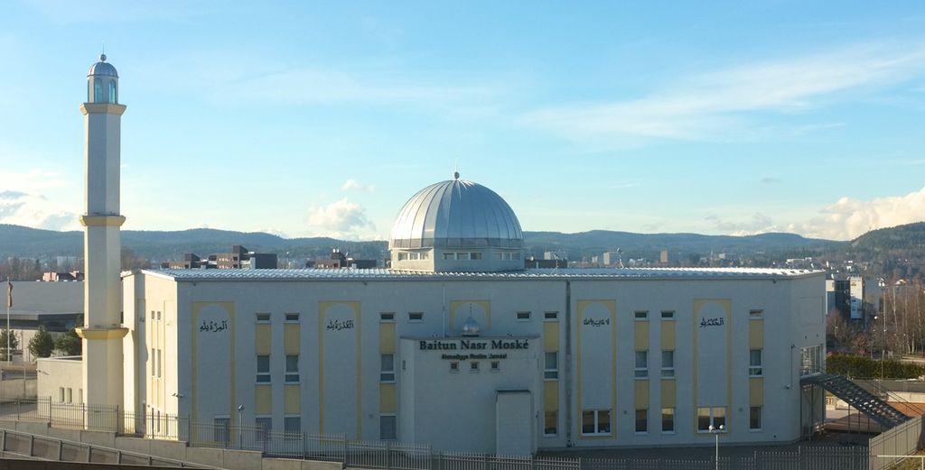 Stor, hvit bygning med kuppel midt på taket og et høyt, smalt tårn på venstre side. Foto.