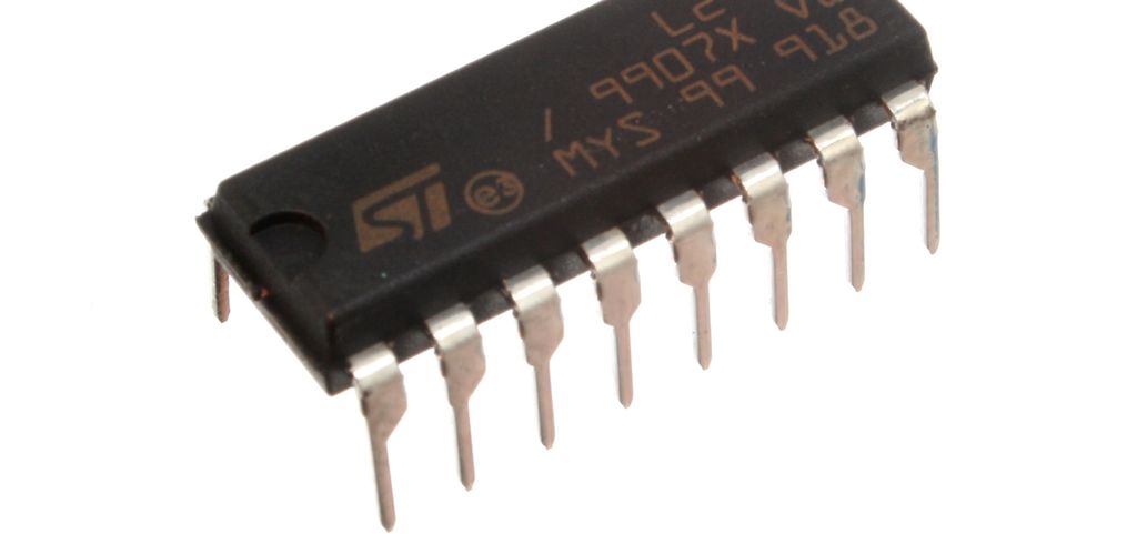 Svart, firkanta elektronisk komponent med åtte synlige tilkoplingspinner på den ene langsida. Foto.