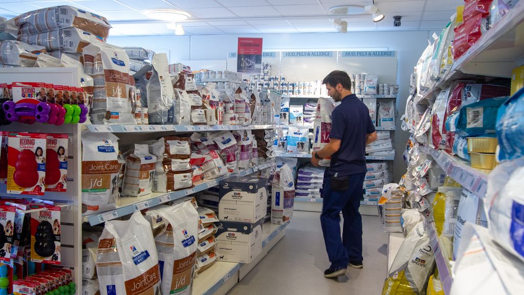 Fagarbeider i dyrebutikk setter på plass varer i hyllene. Foto.