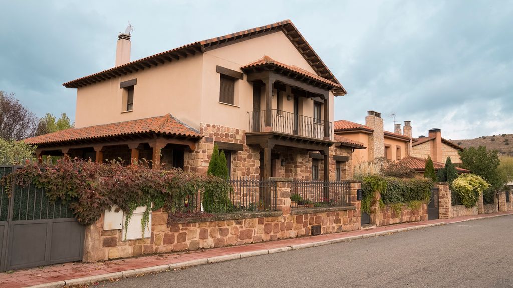 En enebolig av lys murstein med gjerde rundt. Foto.