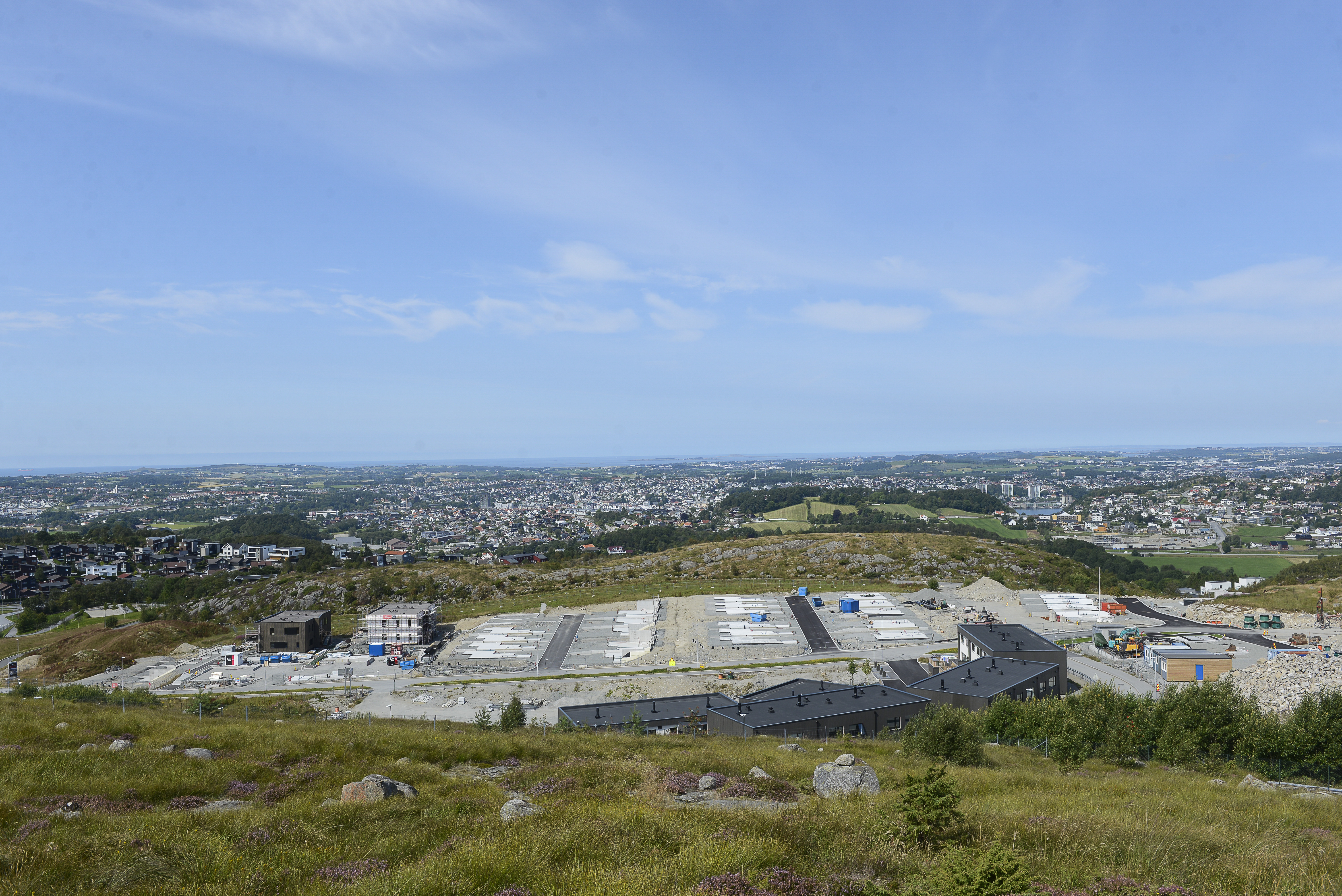 Et planert område med byggeaktivitet der nye hus skal bygges. Naturområder med trær og berg rundt. Foto. 
