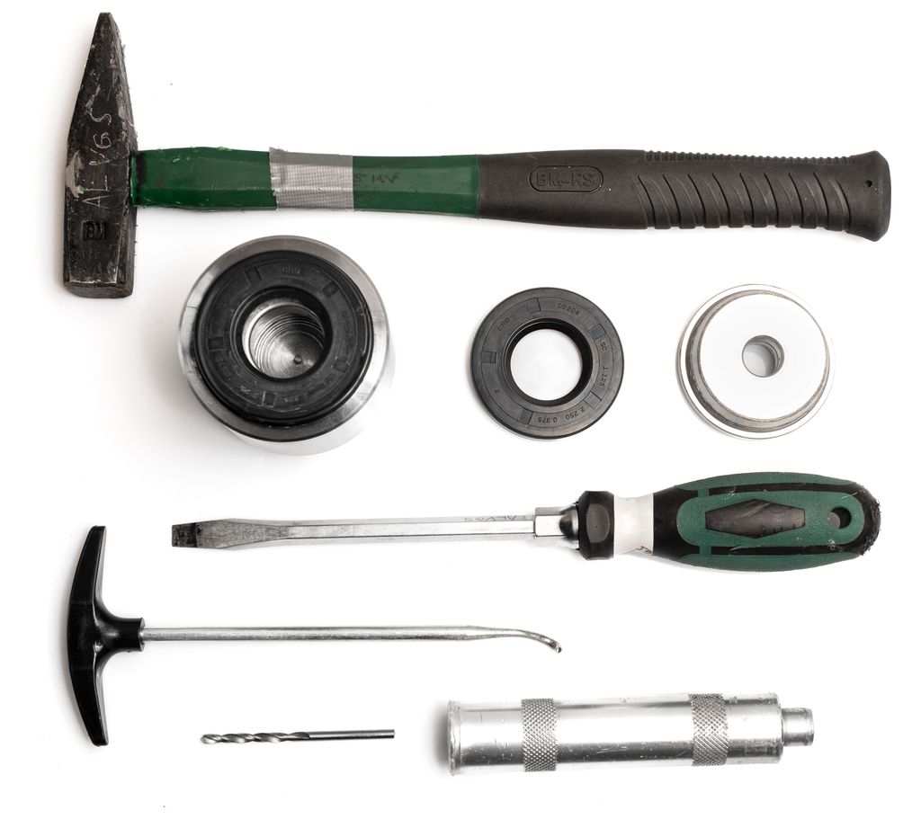 Ulike verktøy ligger sammen med en gummiring: hammer, skrujern, trekkrok, bor, hylse og dor. Foto.