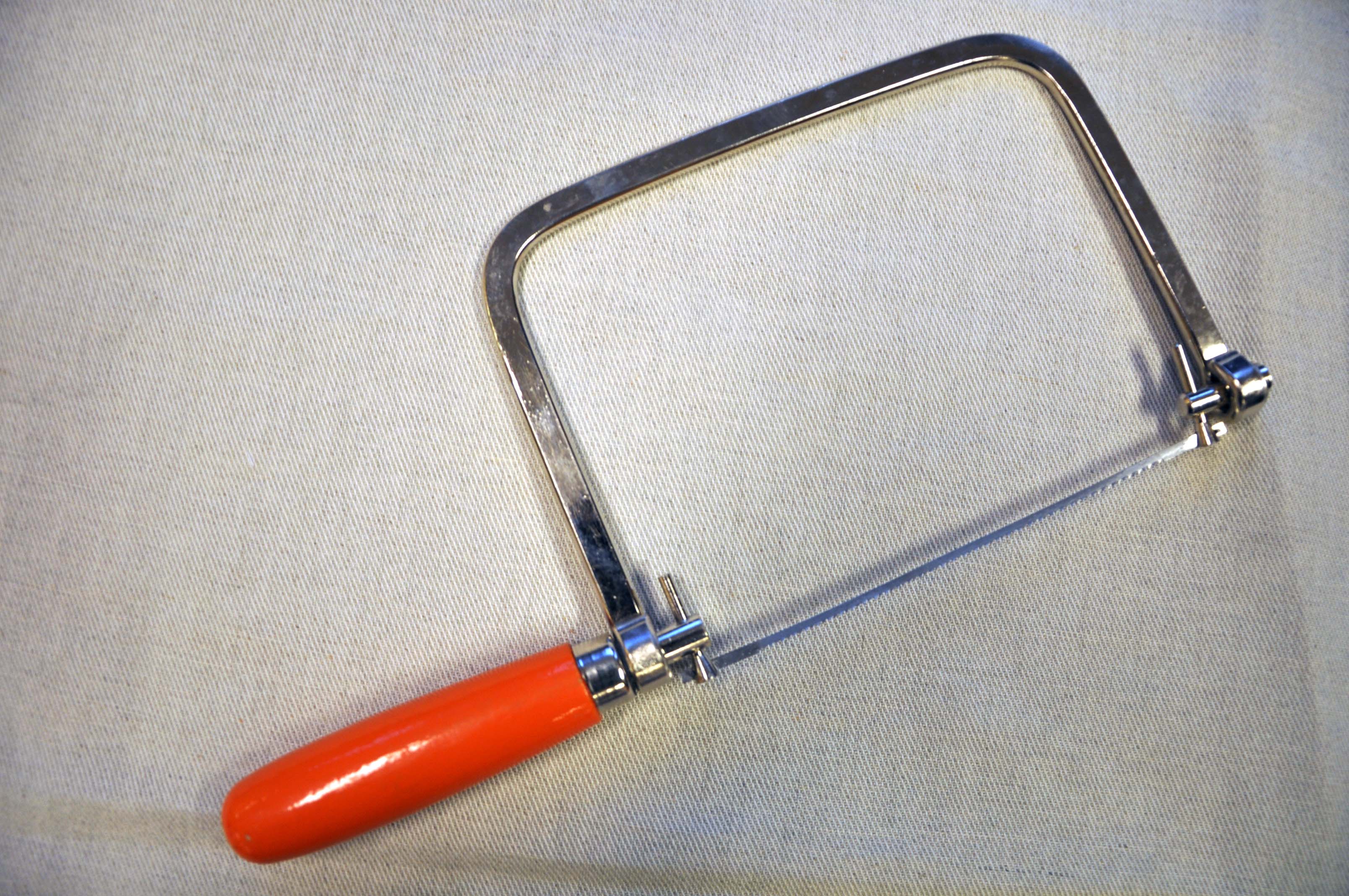 Buesag med rødt håndtak. Foto.