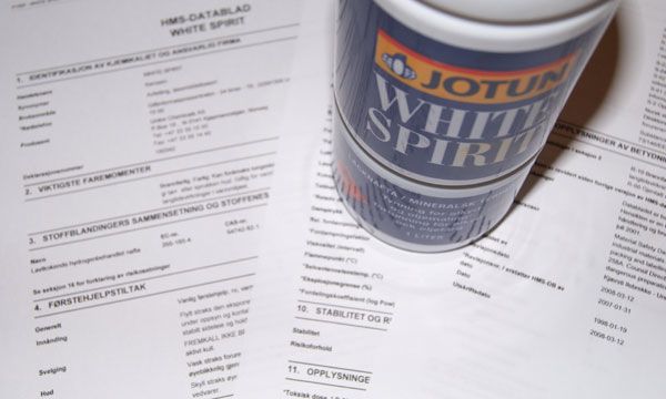 Ei plastflaske med White Spirit står oppå eit datablad. Foto.