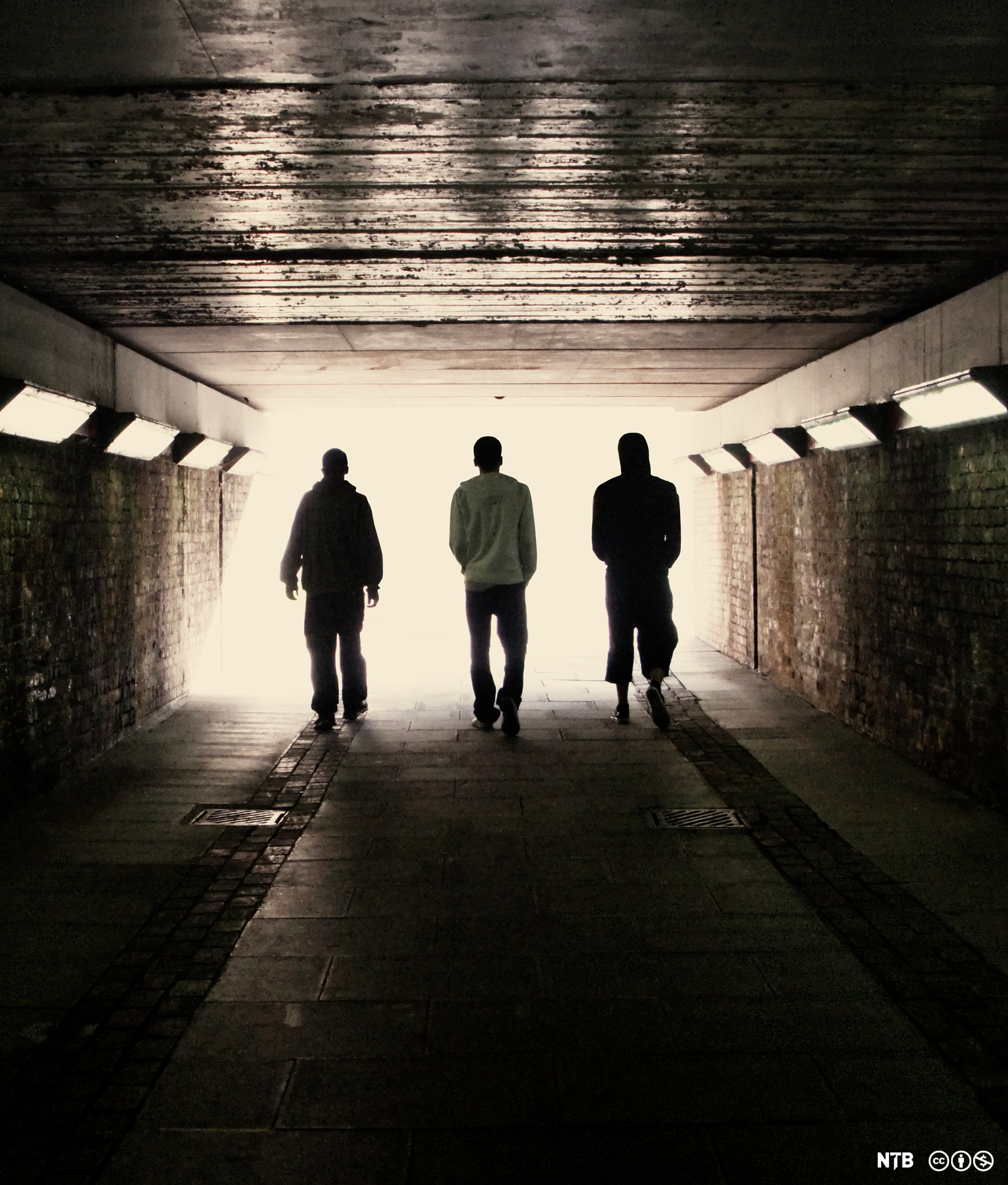 Tre ungdommer går gjennom en undergang. Foto. 