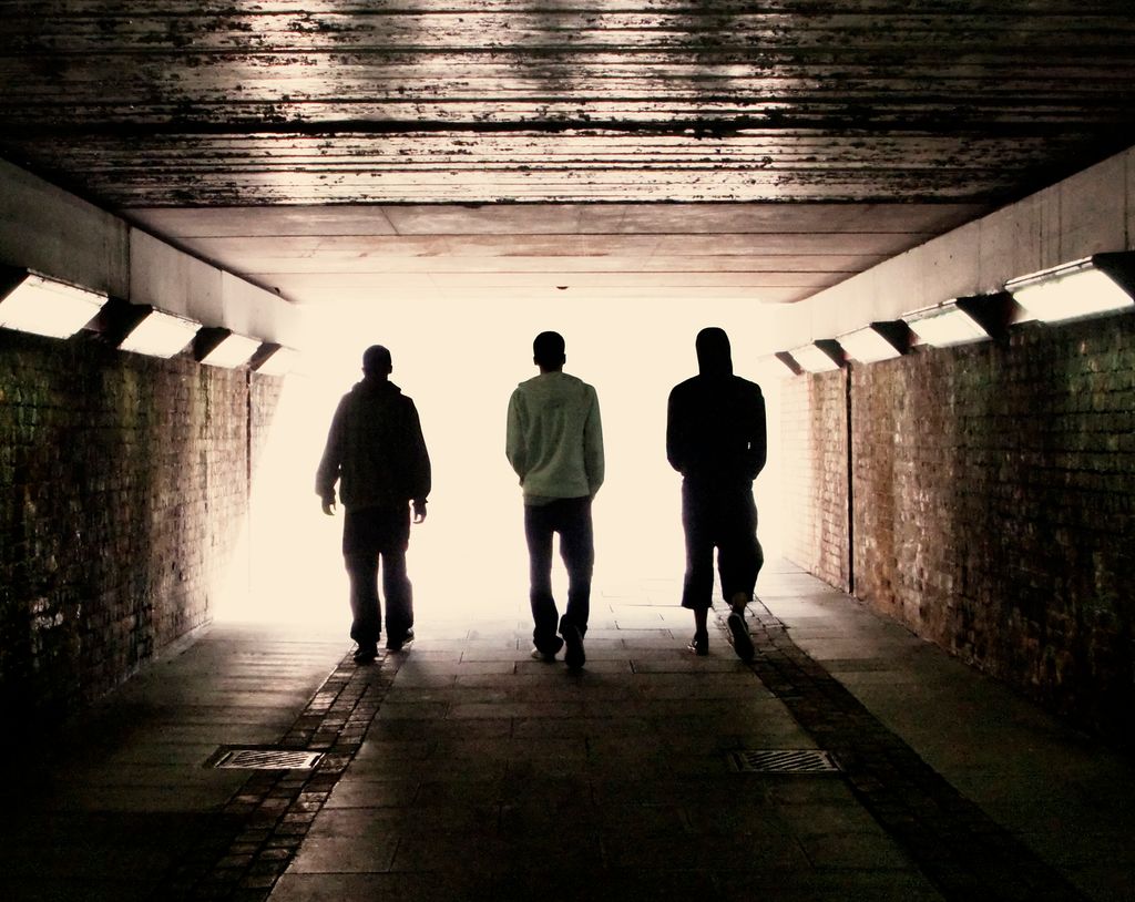 Tre ungdommer går gjennom en undergang. Foto.