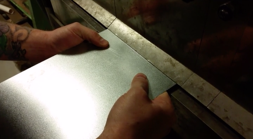 Tynn stålplate legges i knekkemaskin. foto.