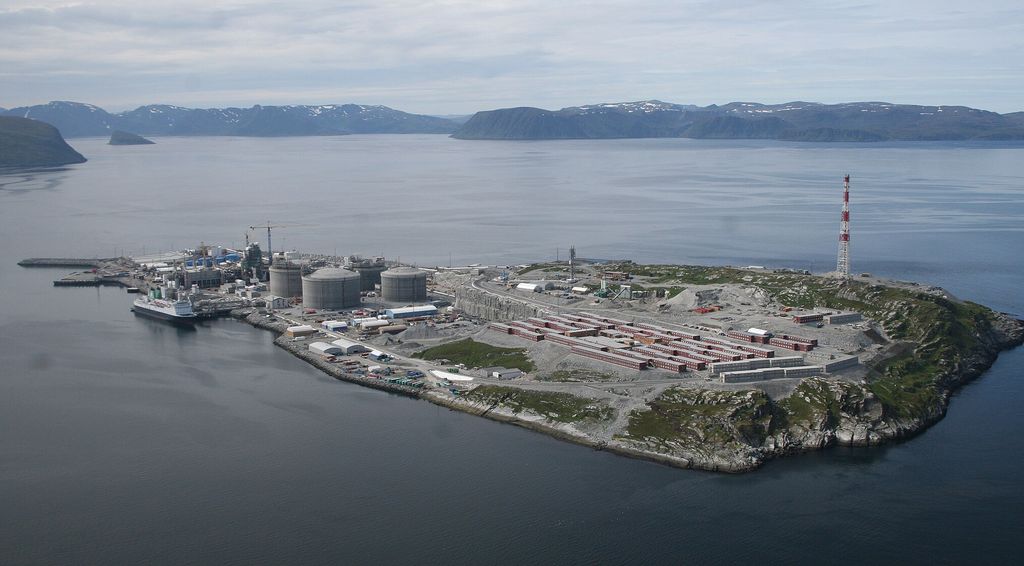 Øy som mer eller mindre er dekket av industriinstallasjoner, som tanker, konteinere og kraner. Et skip ligger til havn. Foto.