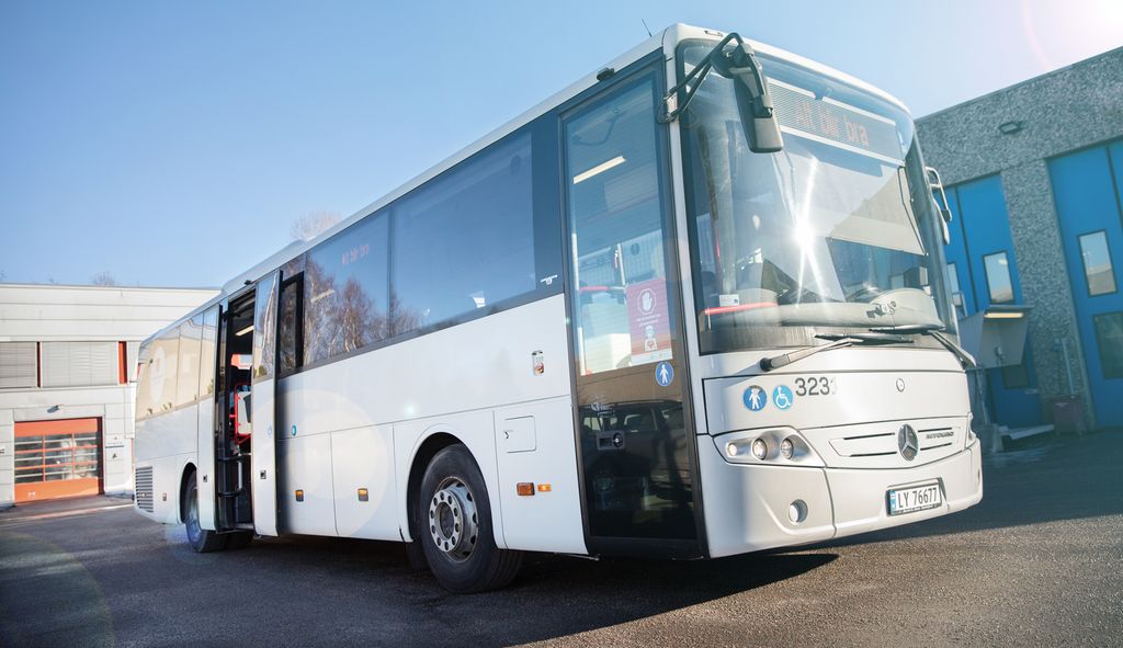 Bilde av en hvit buss, fotografert fra sida.