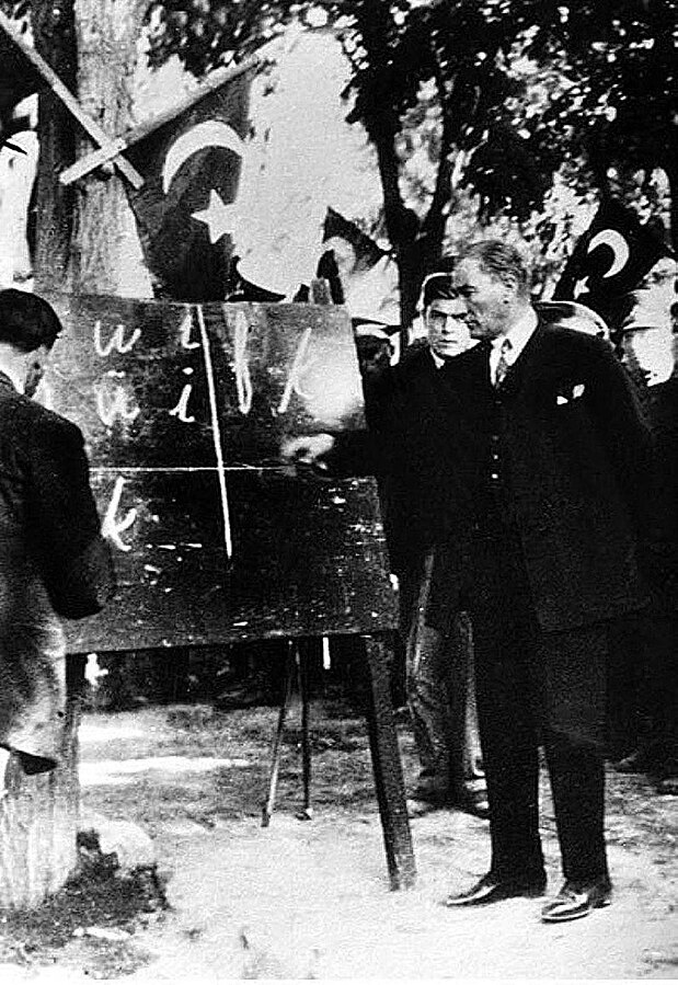 Den tyrkiske presidenten Mustafa Kemal Atatürk peikar på ei tavle med latinske bokstavar. Svart/kvitt-foto.