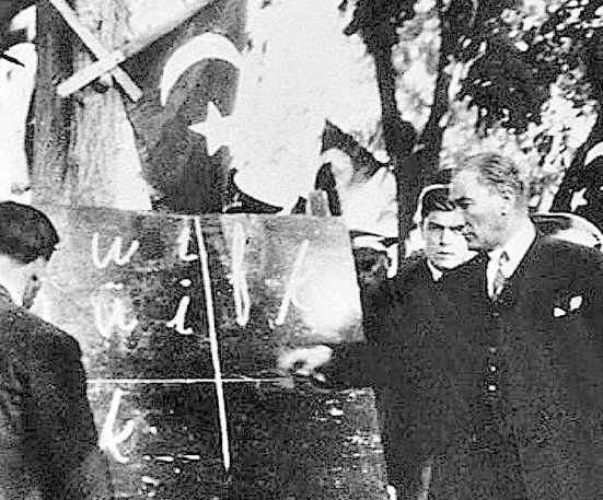 Den tyrkiske presidenten Mustafa Kemal Atatürk peikar på ei tavle med latinske bokstavar. Svart/kvitt-foto.