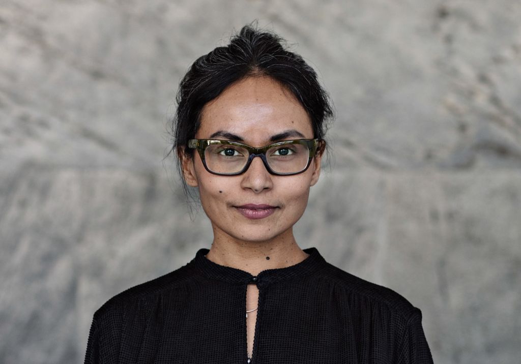 Portrett av sjølvsikker forretningskvinne som står opp mot ein vegg. Foto.