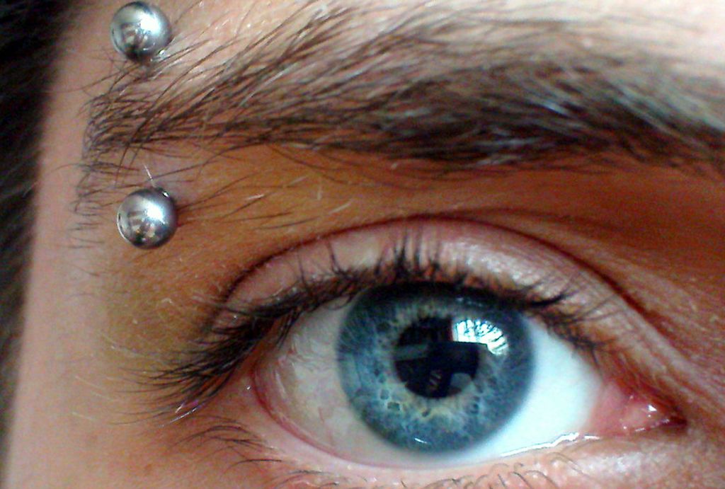 Nærbilete av eit auge med ei piercing i augnebrynet. Foto.