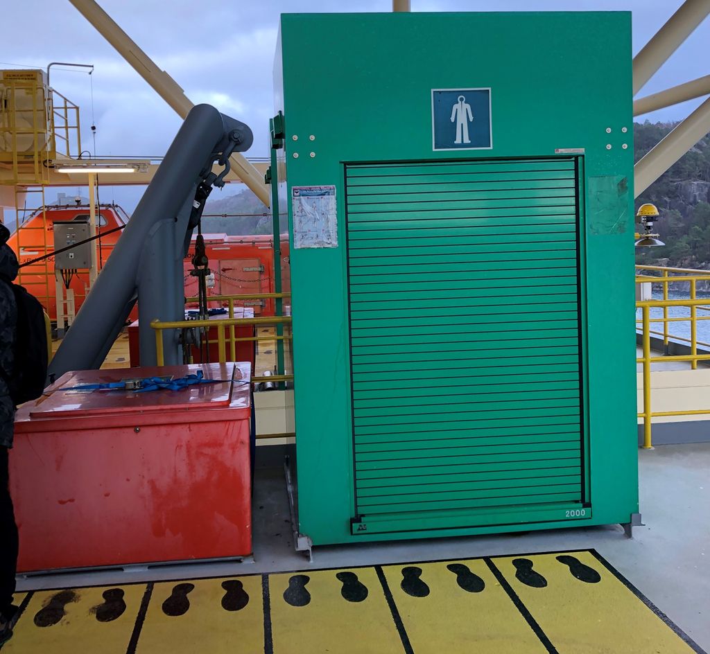 Ved livbåten er en mønstringsstasjon med overlevingsdrakter og oppstillingsplass. Foto.