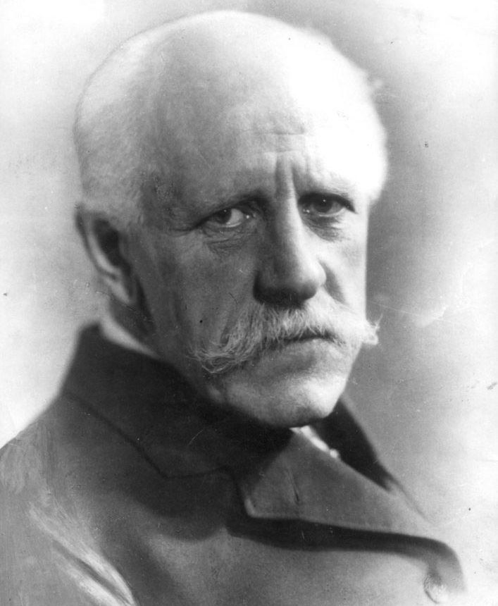 Portrett av ein eldre mann med kvitt hår og bart. Han har frakk på seg. Mannen er Fridtjof Nansen. Svart-kvitt foto.