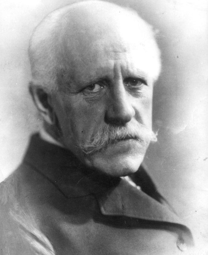 Portrett av en eldre mann med hvitt hår og bart. Han har frakk på seg. Mannen er Fridtjof Nansen. Svart-hvitt foto.