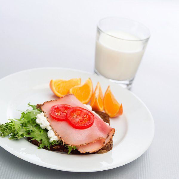 Frokost som består av frukt, brødskiver med pålegg og melk. Foto.