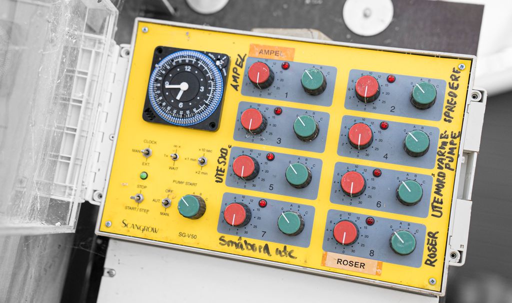 Boks med røde og grønne skrubrytere for styring av vanning. Foto.