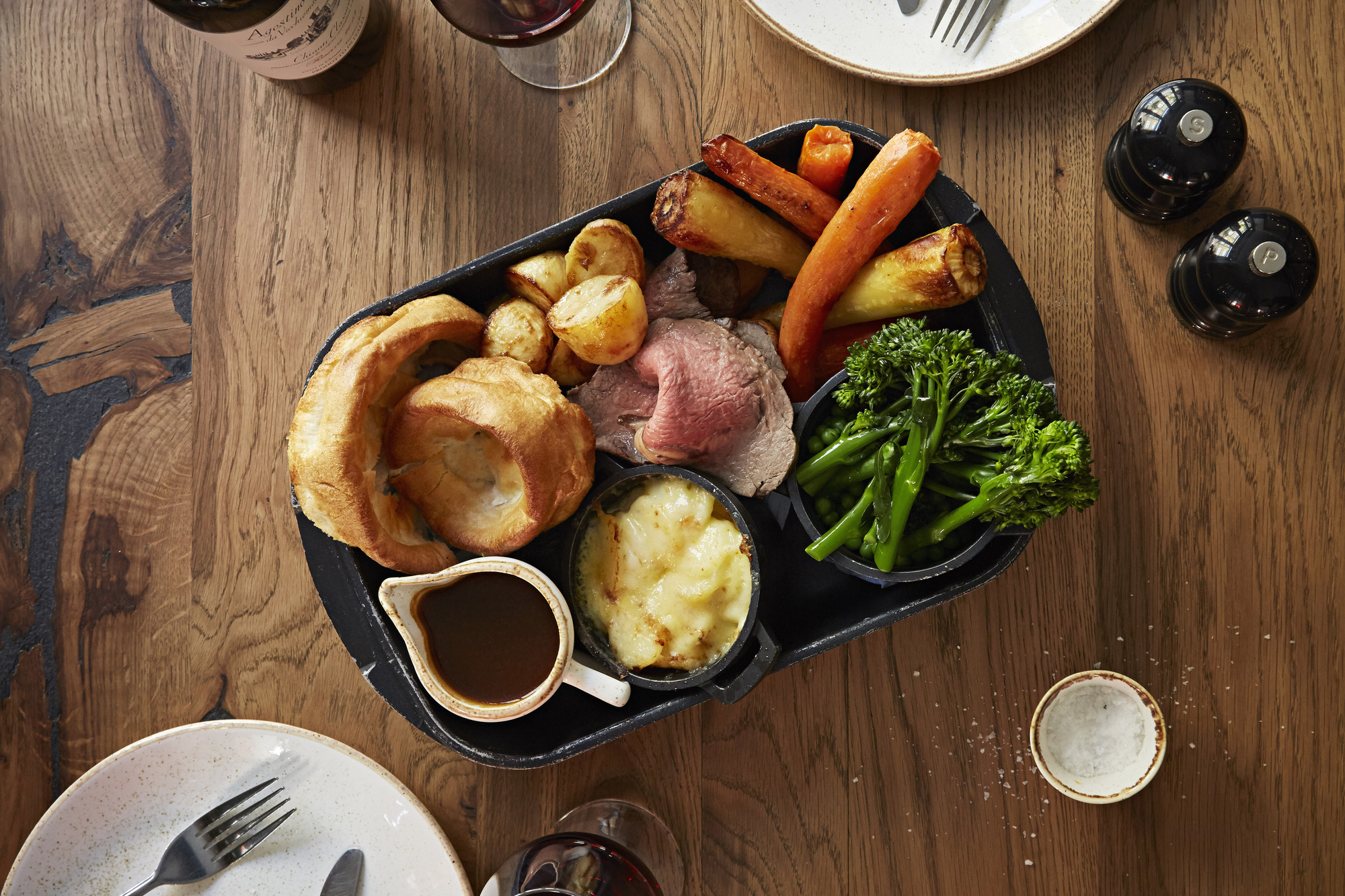 Roastbiff, brokkoli, poteter, yorkshirepudding og brun saus på et serveringsfat. Foto.