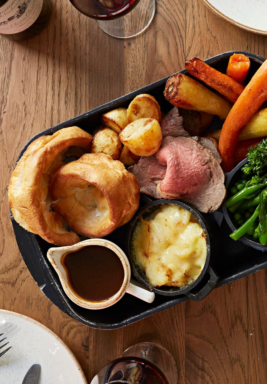 Roastbiff, brokkoli, poteter, yorkshirepudding og brun saus på et serveringsfat. Foto.
