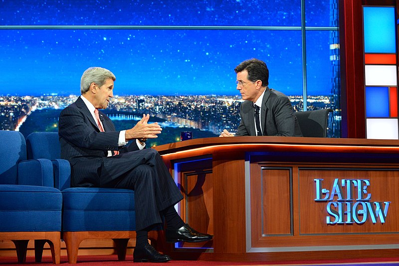 Secretary John Kerry makes an appearance on The Late Show with Stephen Colbert. The two men are sitting on either side of a desk, in deep conversation. 