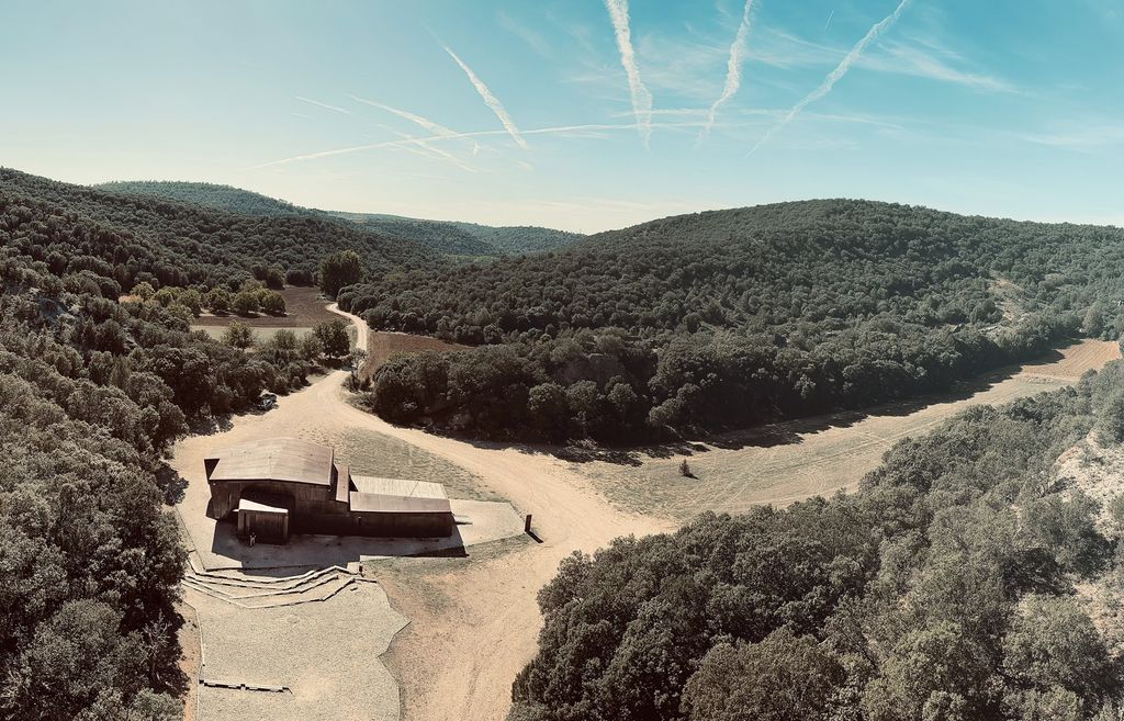 Luftfoto av et bygg ved enden av en vei i et skogkledd landskap. Foto.