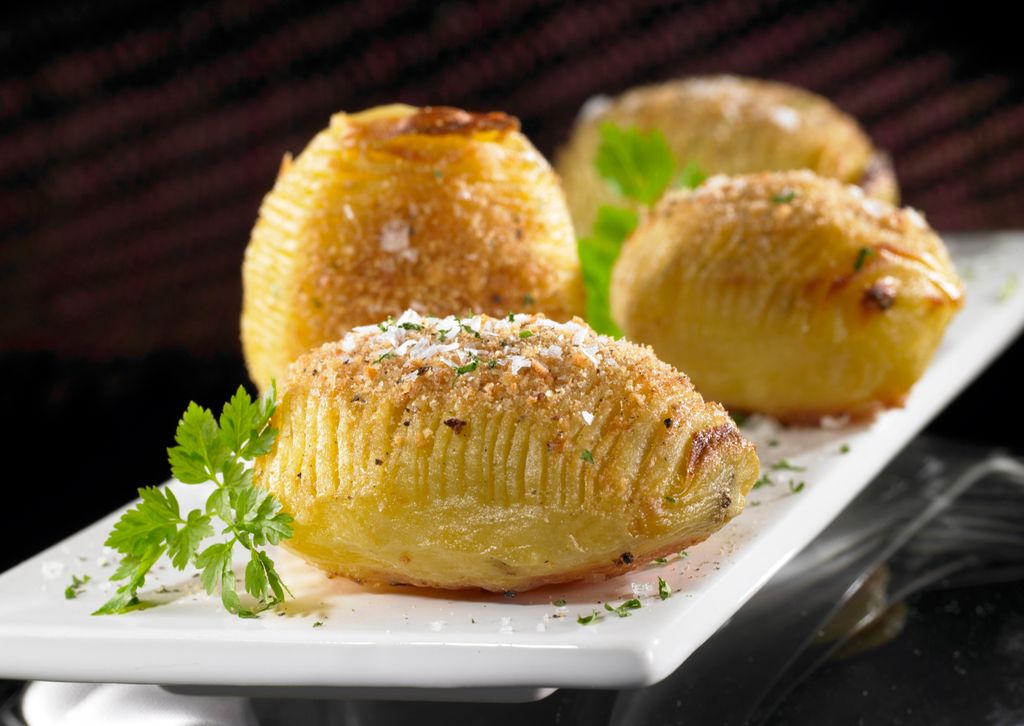 Hasselbackpoteter på et hvitt fat. Foto. 