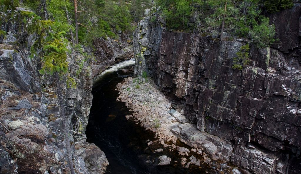 Juv med svært bratte, nesten loddrette fjellsider. Ei elv renn nedst i juvet. Furutre på kvar side av juvet. Foto.