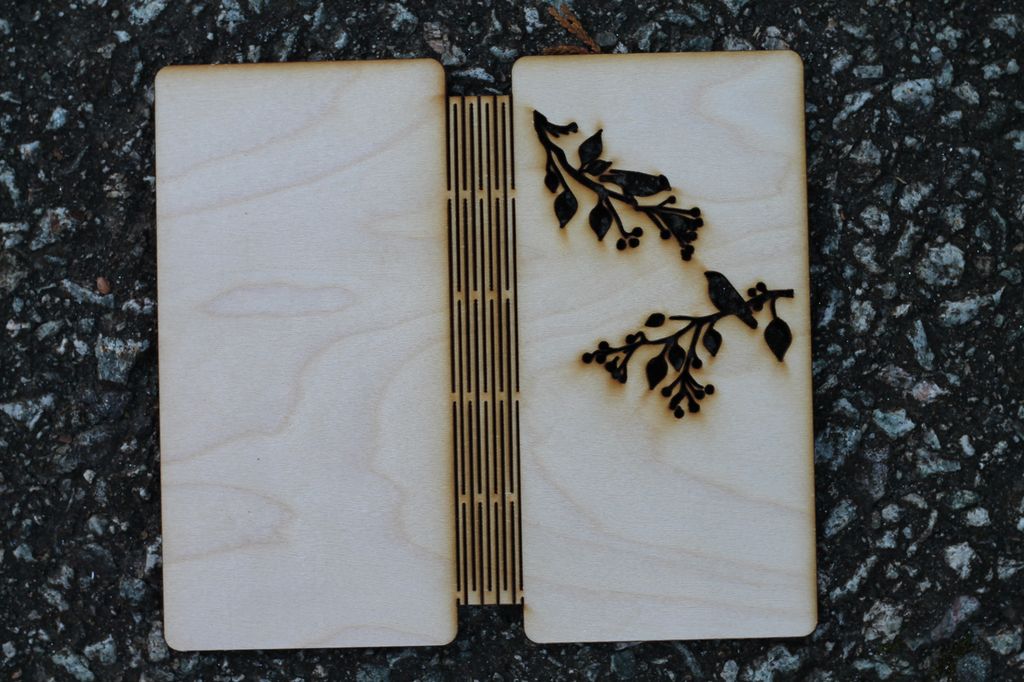 Mobildeksel i flyfiner med silhuett av fugler på grener skjært ut. Foto