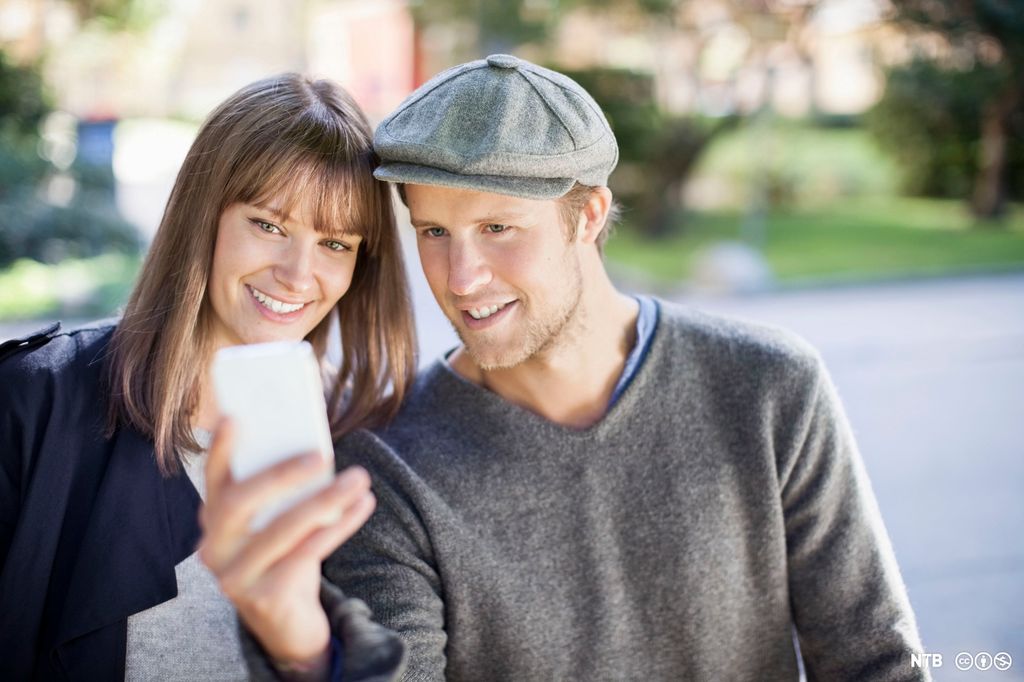Et ungt par tar en selfie sammen utendørs. Foto.