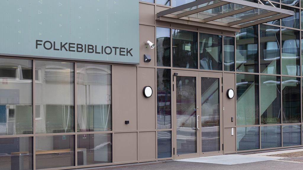 Eit inngangsparti på ein større institusjonell bygning. Eit skilt fortel at dette er eit folkebibliotek. Foto.