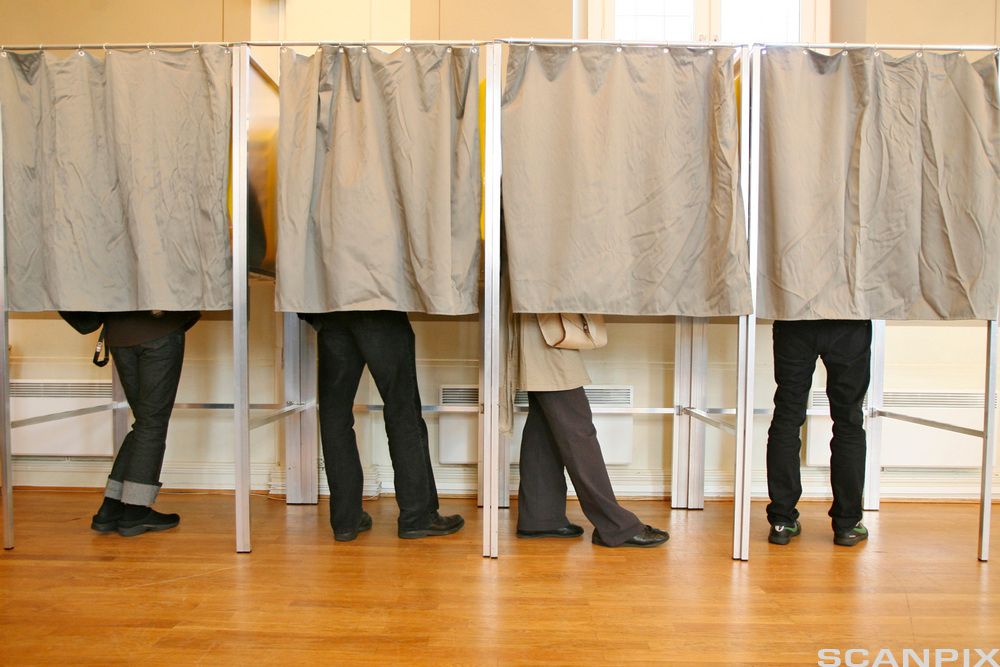 Fire avlukker med forheng. Beina til fire personer synes under forhengene. Foto.