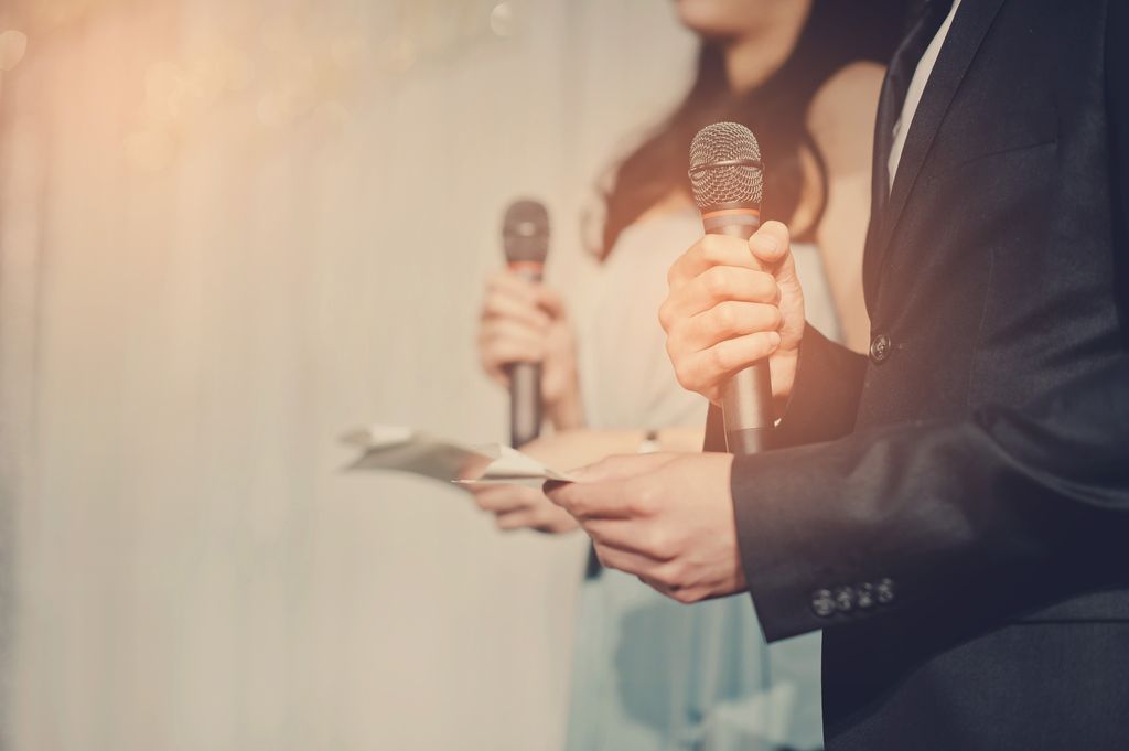 En kvinne og en mann framfører noe med hver sin mikrofon og hvert sitt manus å hånda. Foto.