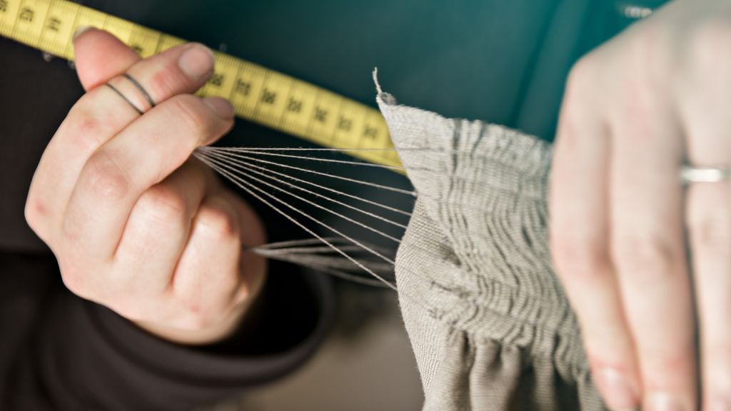 Fotografi av hender som arbeider med en rynkesøm på et forkle.