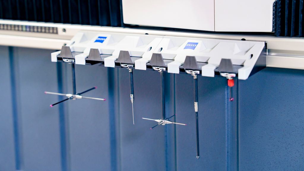 Fem ulike måleprober med røde spisser henger på en maskin. Foto.