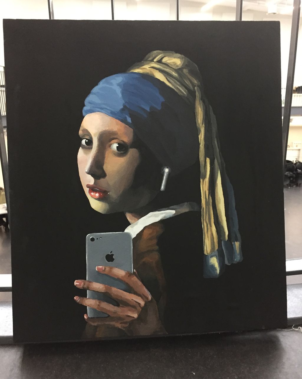 Maleri av en pike med perleøredobb og turban som tar selfie. Foto.