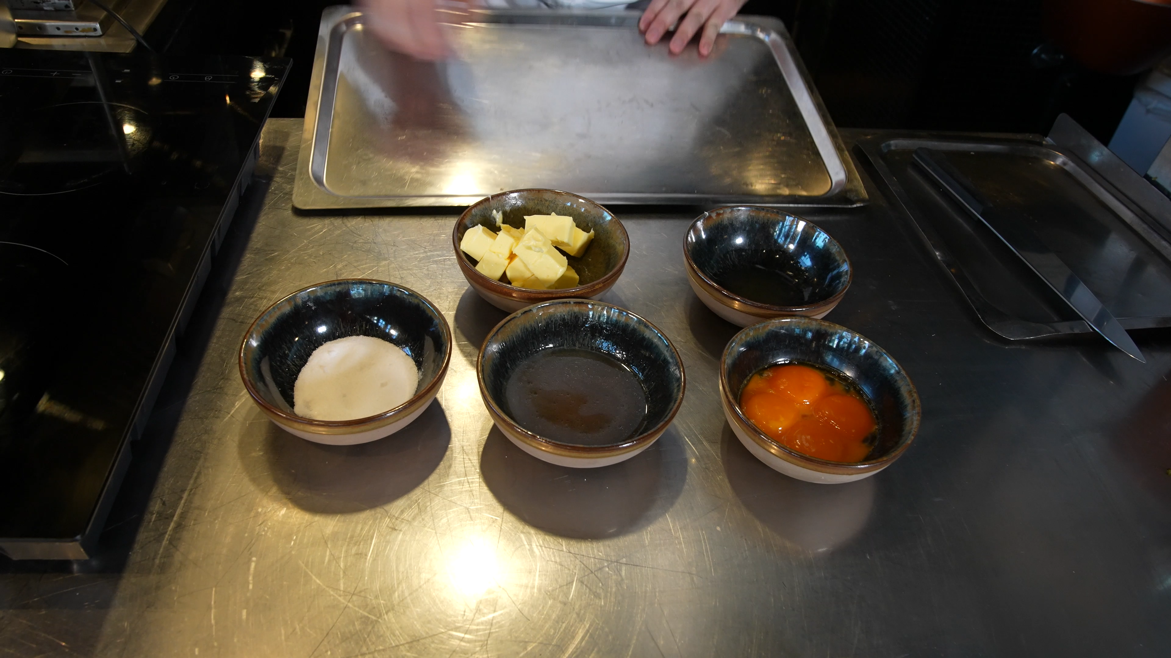 Fem skåler med forskjellige ingredienser, som eggeplommer, smør, reduksjon og salt. Foto.